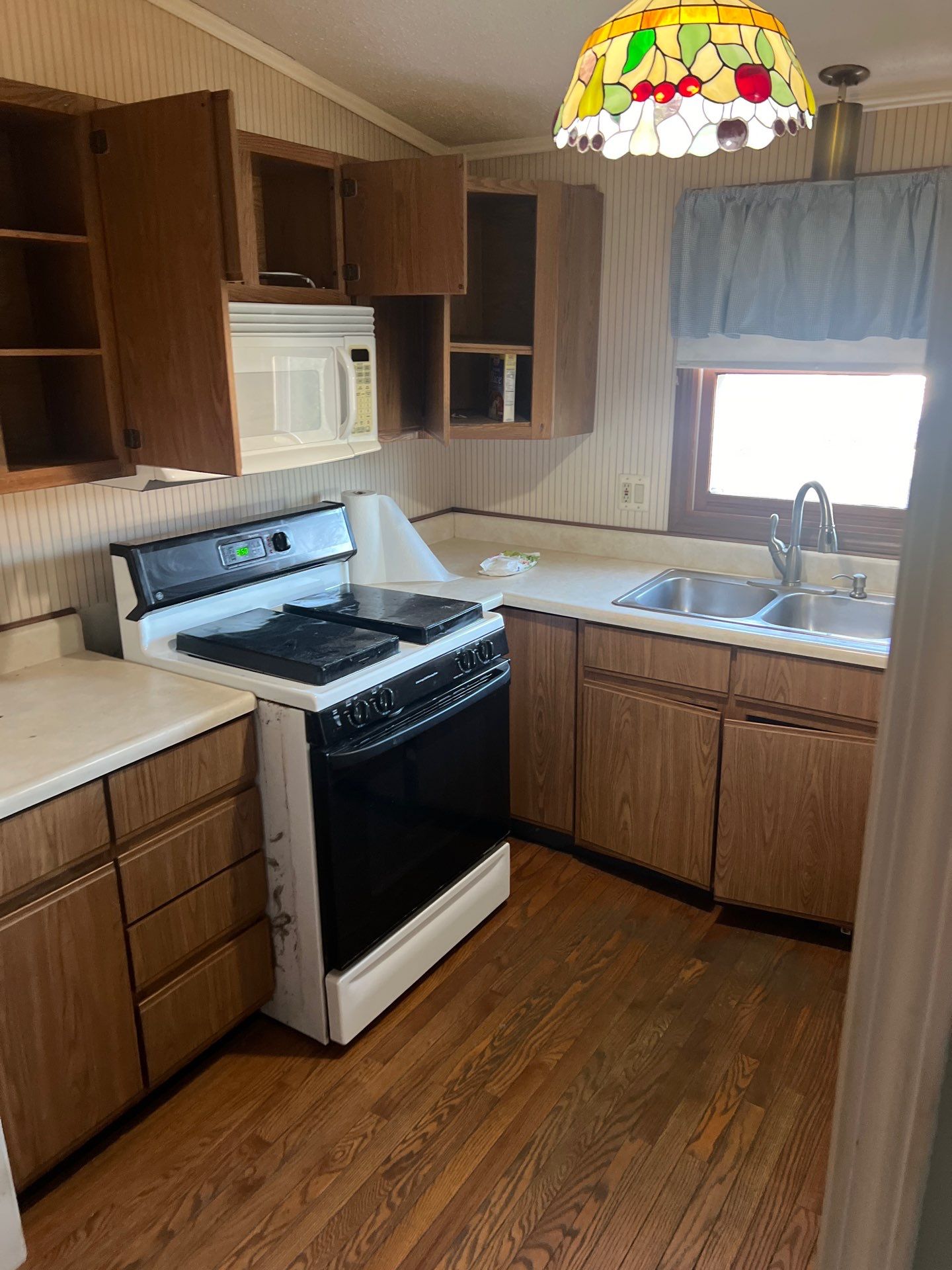 kitchen before remodeling, image shows older oak cabinets and outdated stove